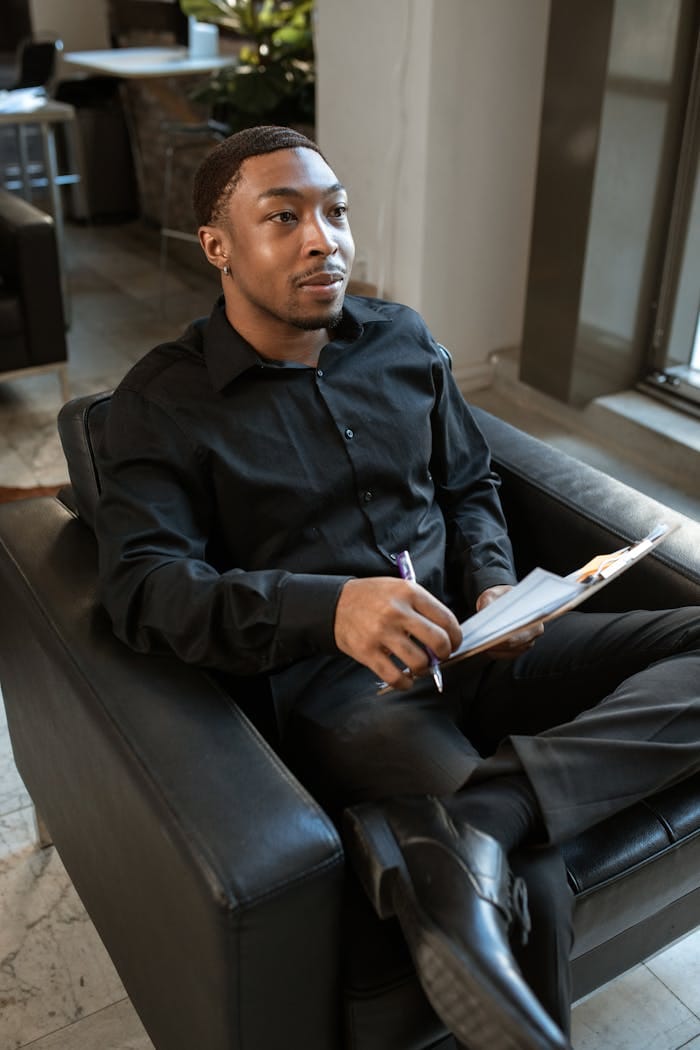 Business professional sitting in a modern office chair, holding a notepad.